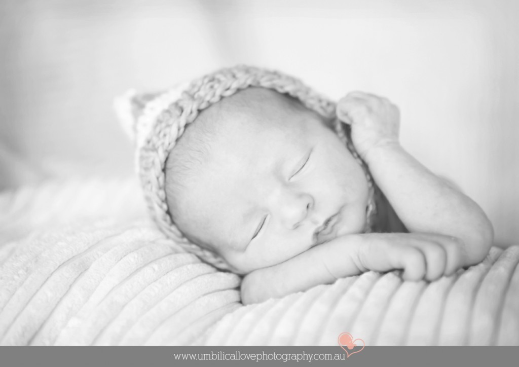 baby sleeping with one arm on his head with a hat on