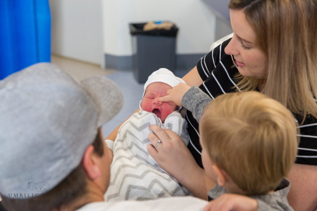 big brother touches newborn brother on the nose
