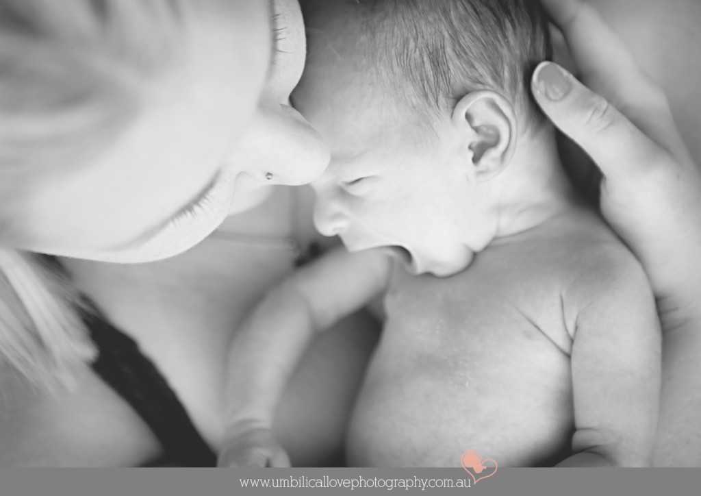 mum holding new baby close while baby yawns