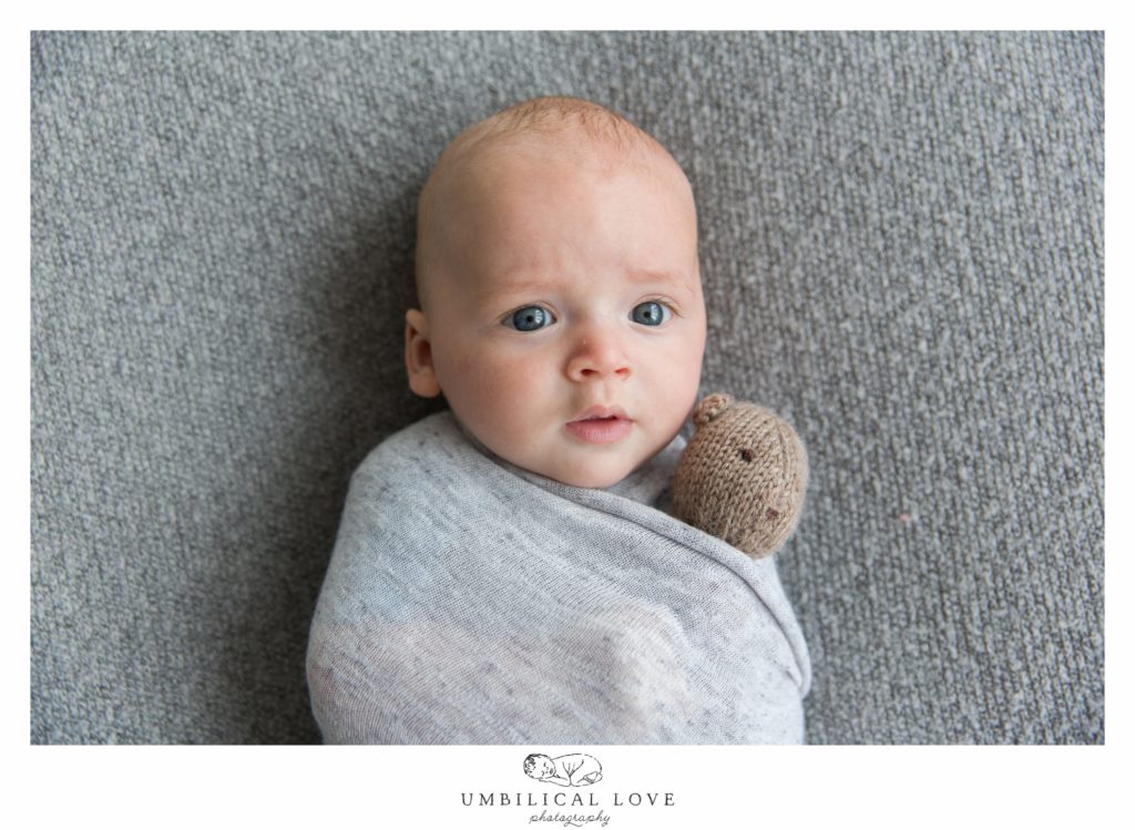 baby staring at camera with teddy in arms
