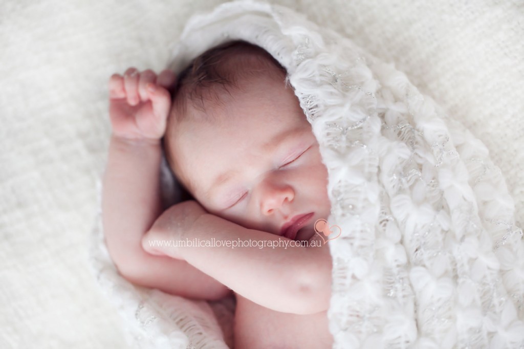 new baby all swaddled with arms crossed over 