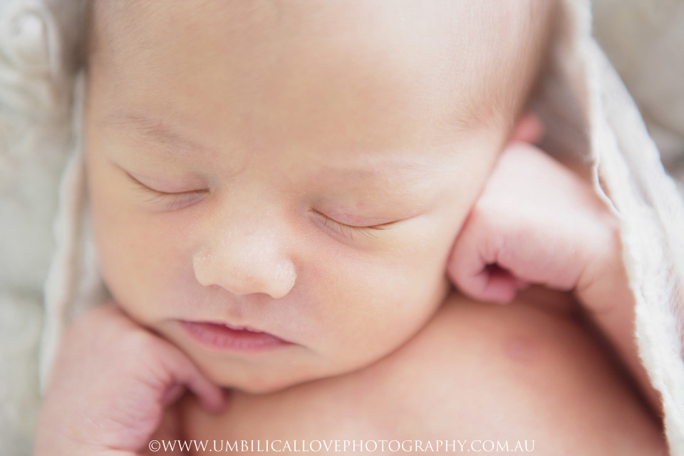 Newborn-Baby-Photographer-Wagga-Wagga very close photo of neborn babys face and her hands curled beside it