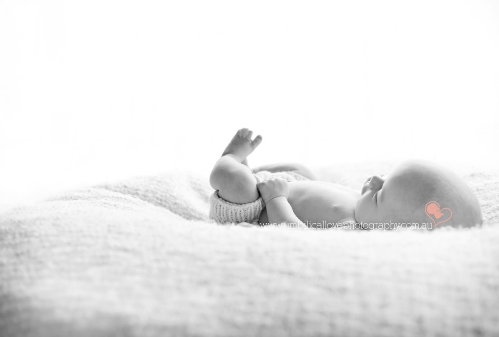 sweet baby boy laying down looking at his toes