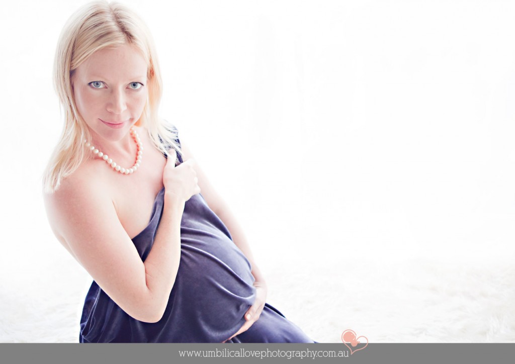 heavily pregnant woman looking at camera holding her belly