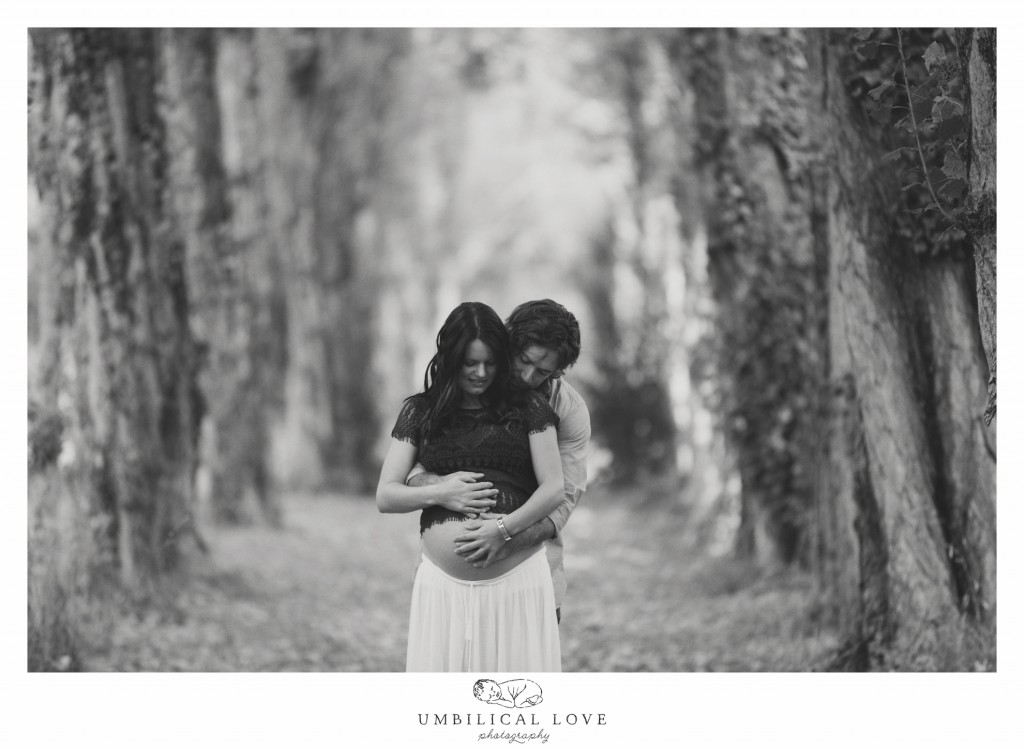 Moody shot of couple looking down at pregnant belly