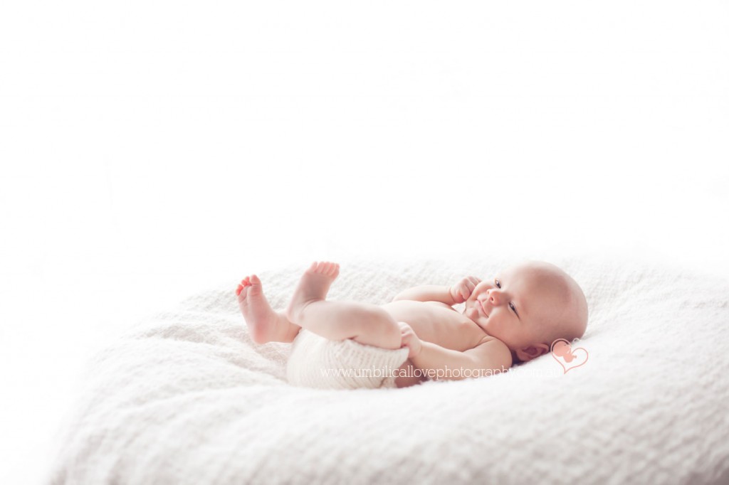 gorgeous and content 6 week old baby with a slight smile on his face laying on a beanbag