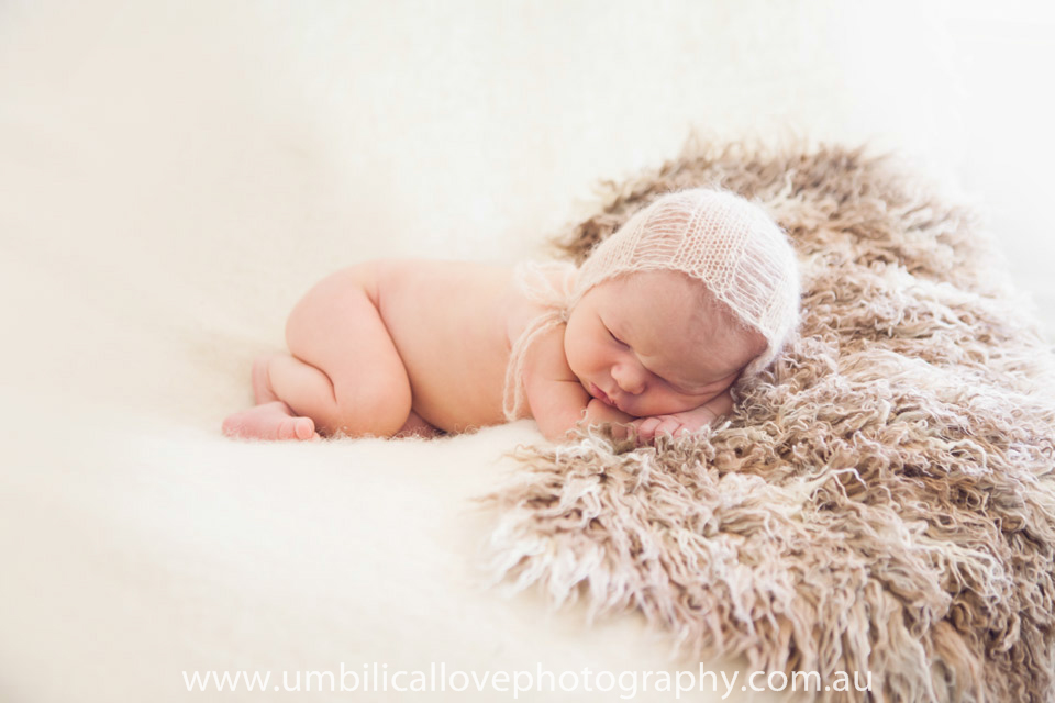 baby sleeping on soft white and brown throws