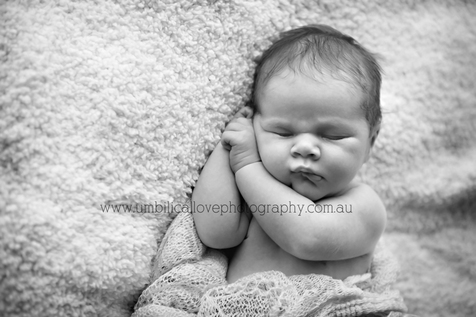 7 day old baby sleeping on his side with both his hands under his head
