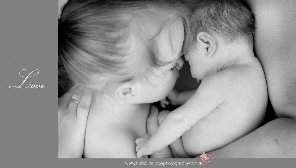 big sister kissing her baby brother in mums arms