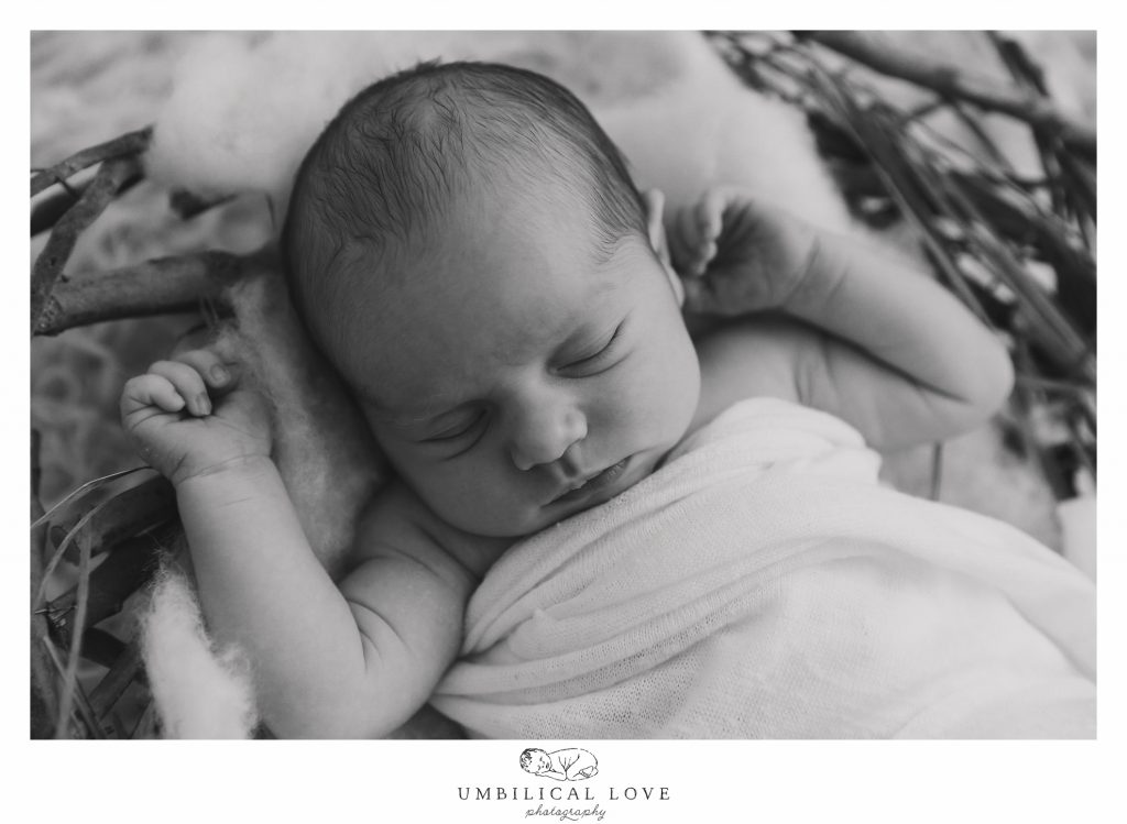 newborn girl with hands out lying in basket 