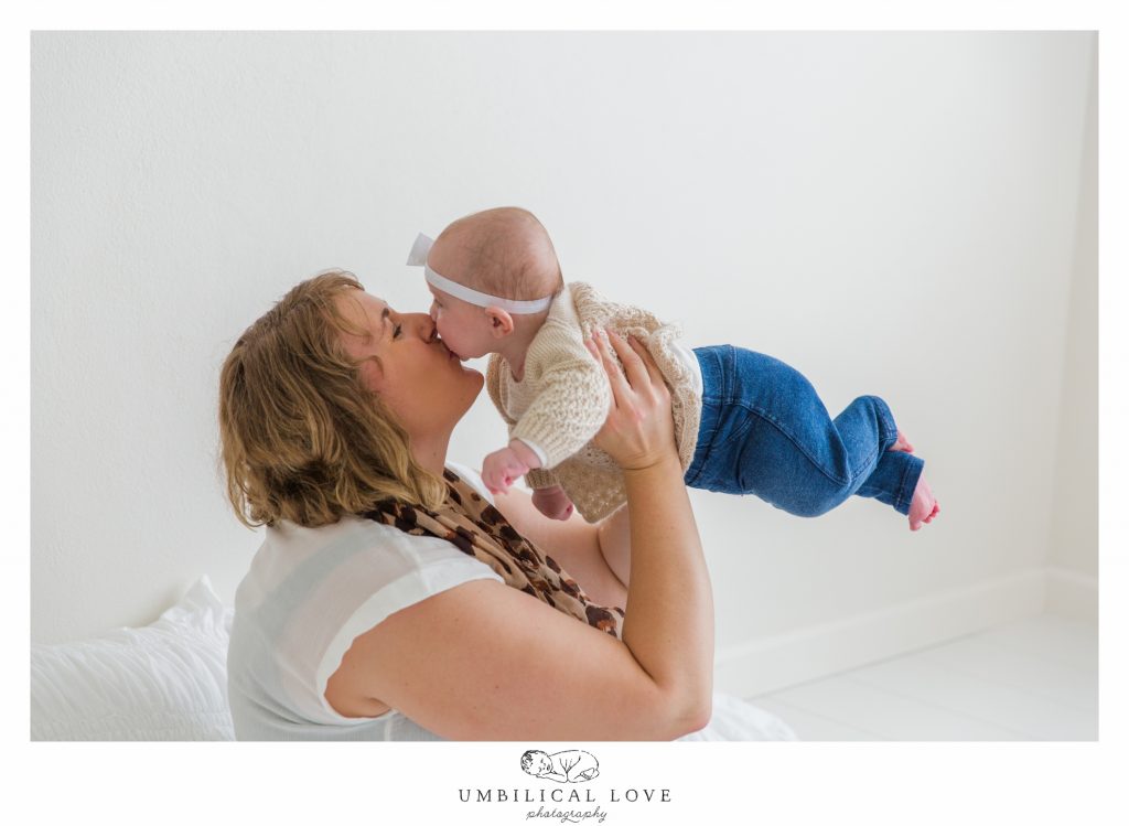mum holding baby up in the air with legs flying out 