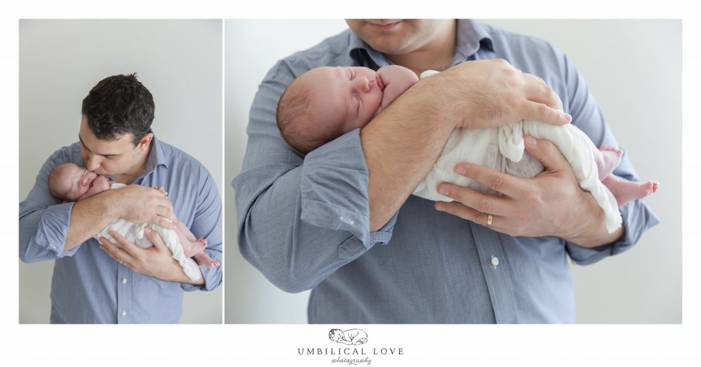 Dad holding and kissing newborn baby daughter 