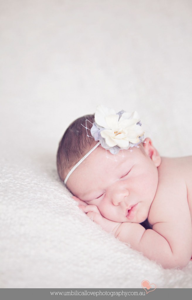 baby sleeping on her hands with a headband on head