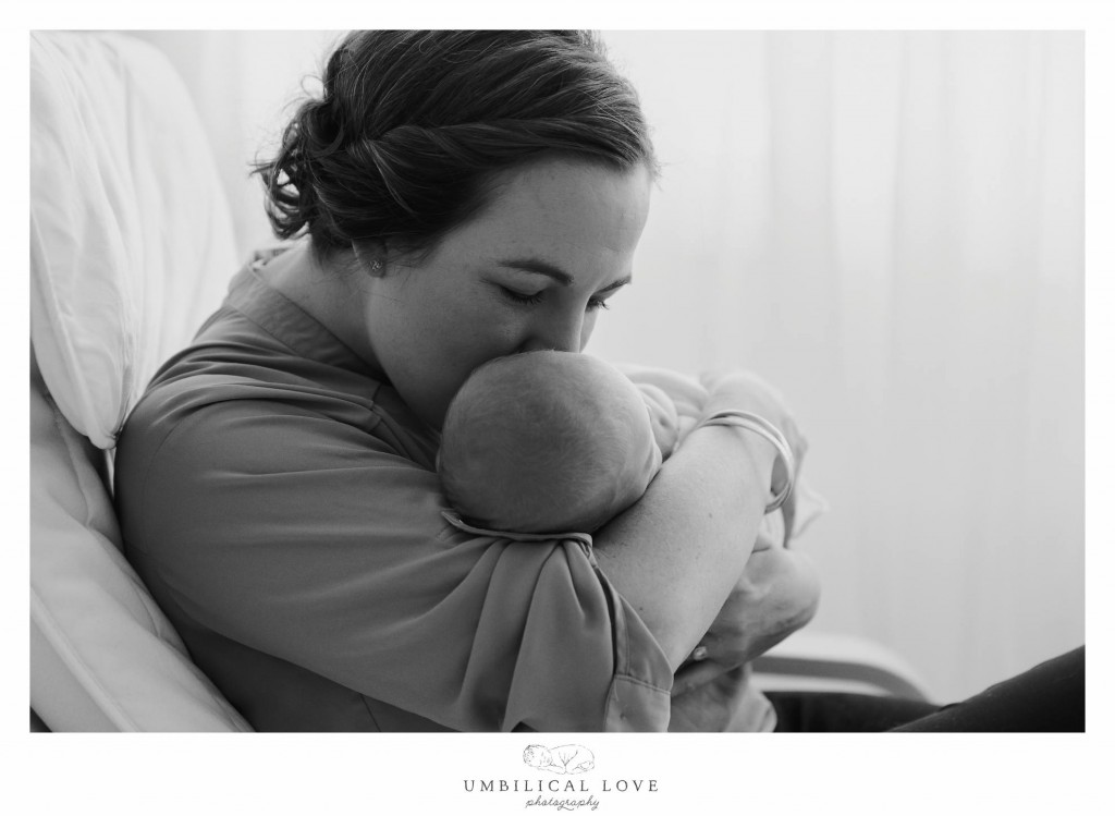 new mum cuddles and kisses her new baby close 