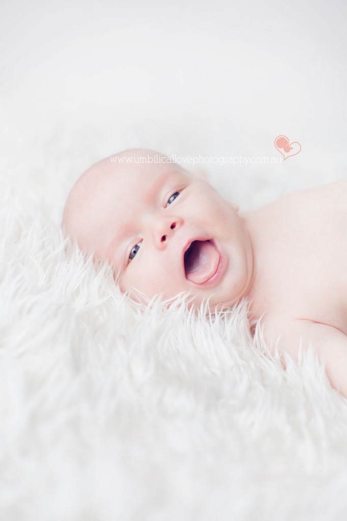 beautiful 6 week old baby with a large smile & laughing looking at the camera 