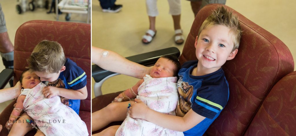 Brother smiles at camera as he holds his baby sister in the hospital