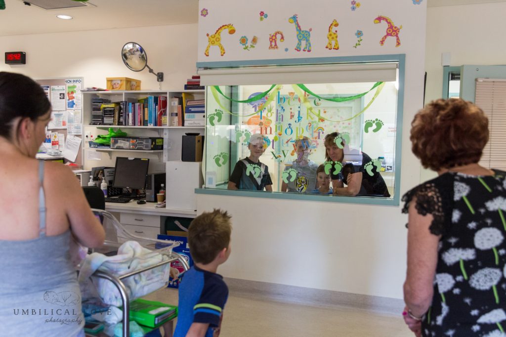 Visitors look through hospital window at new baby 