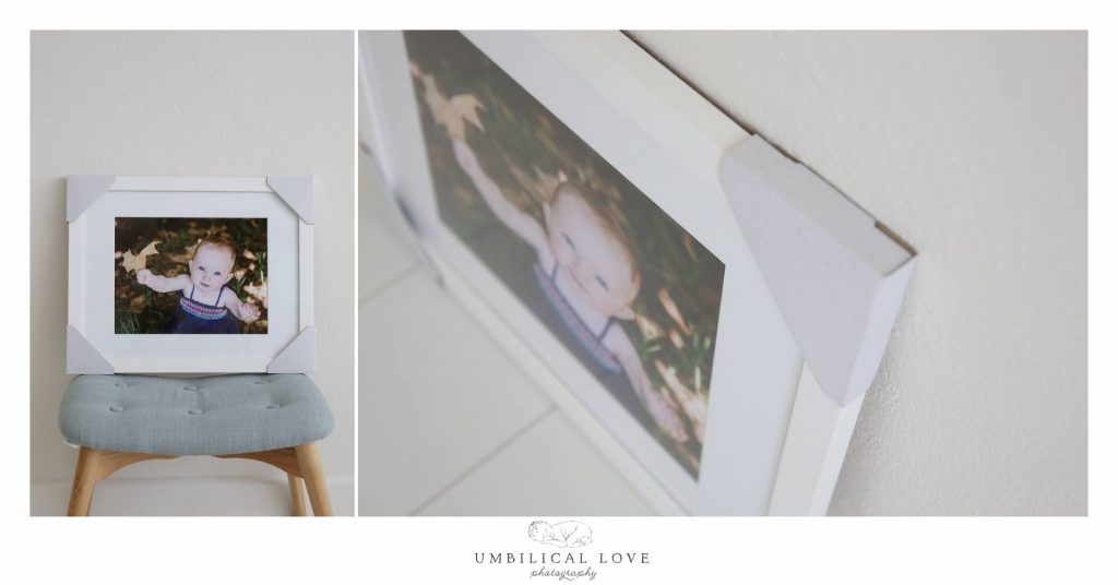 Simple White Frame Fine Art Print Of Baby Girl Holding Up A Leaf Looking AT camera