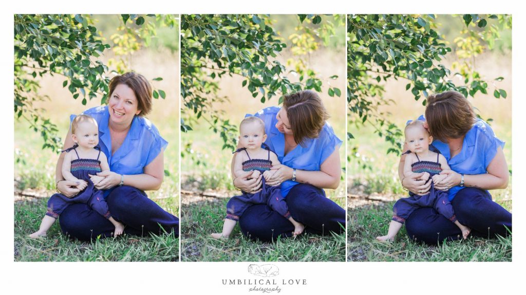 little girl sitting on her mummy's lap in the shade on a sunning day laughing