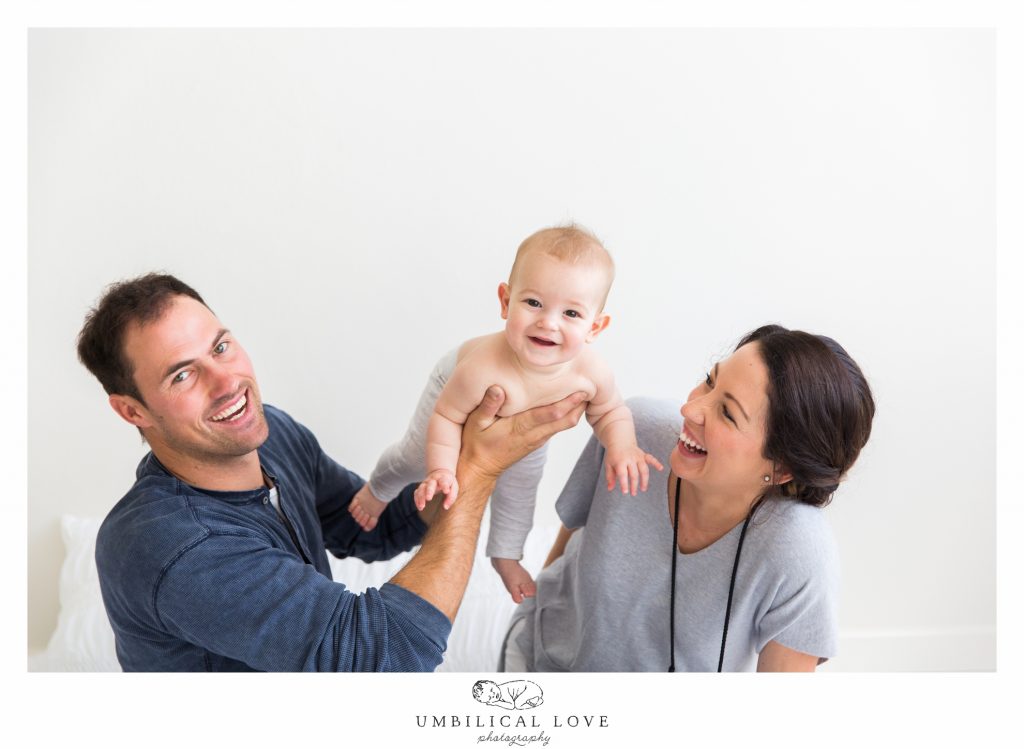 mum and dad smiling while throwing son in the air