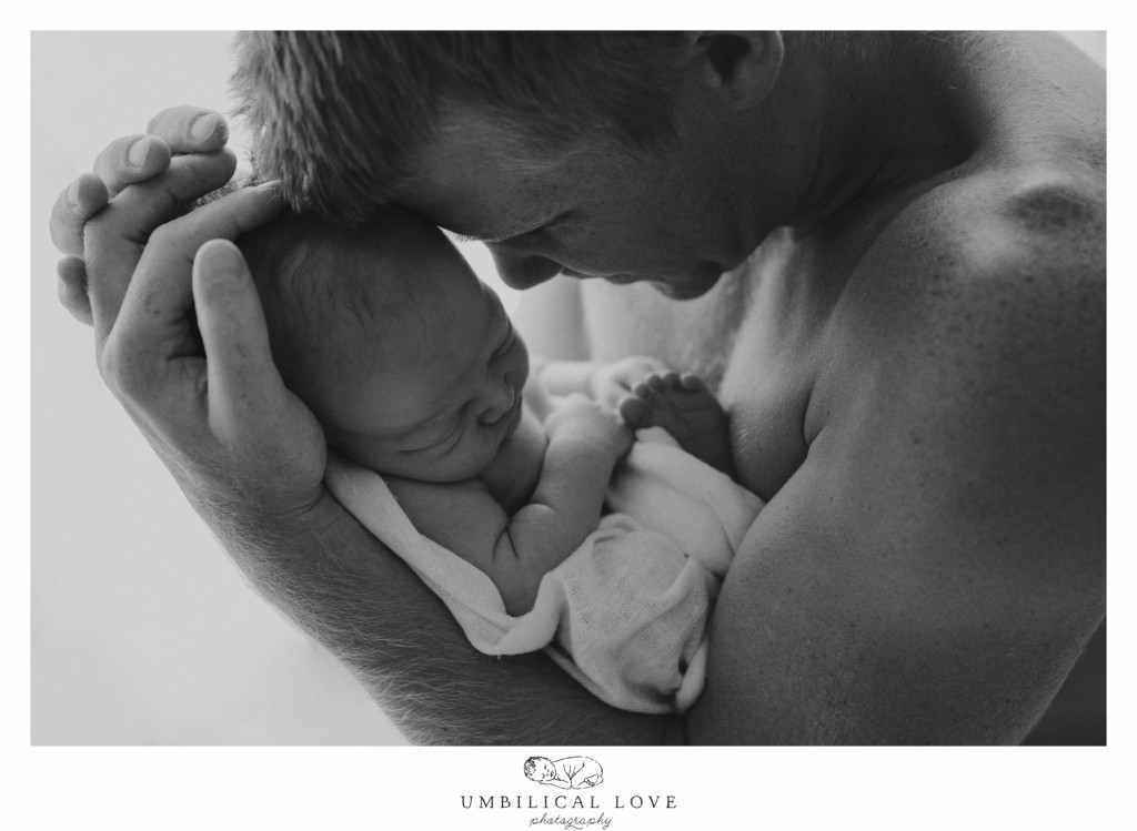 Dad holding newborn son close in his arms