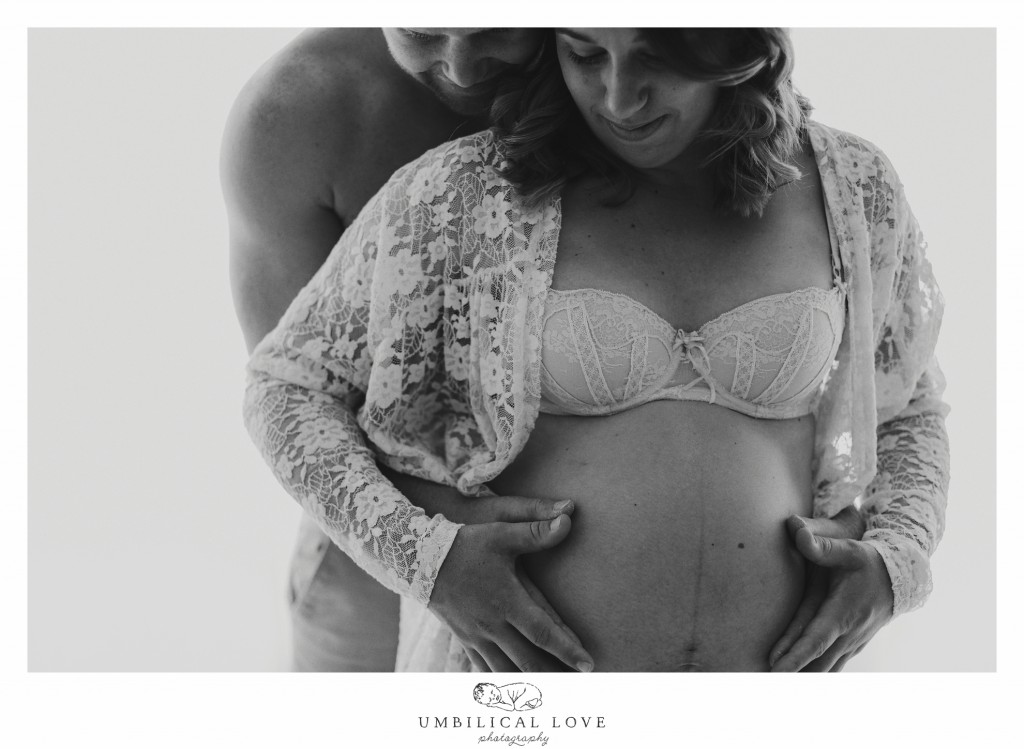 Dad behind mum looking down at pregnant belly