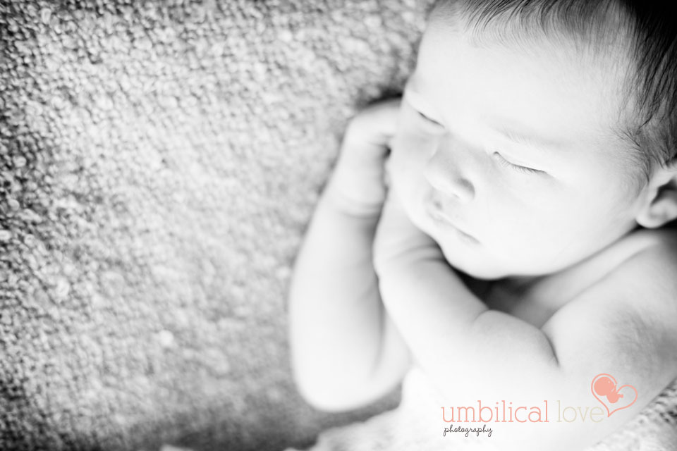newborn baby laying on hands on side