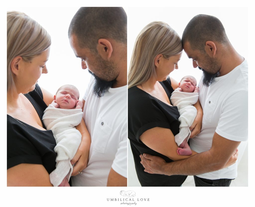 Mum and dad holding baby girl together 