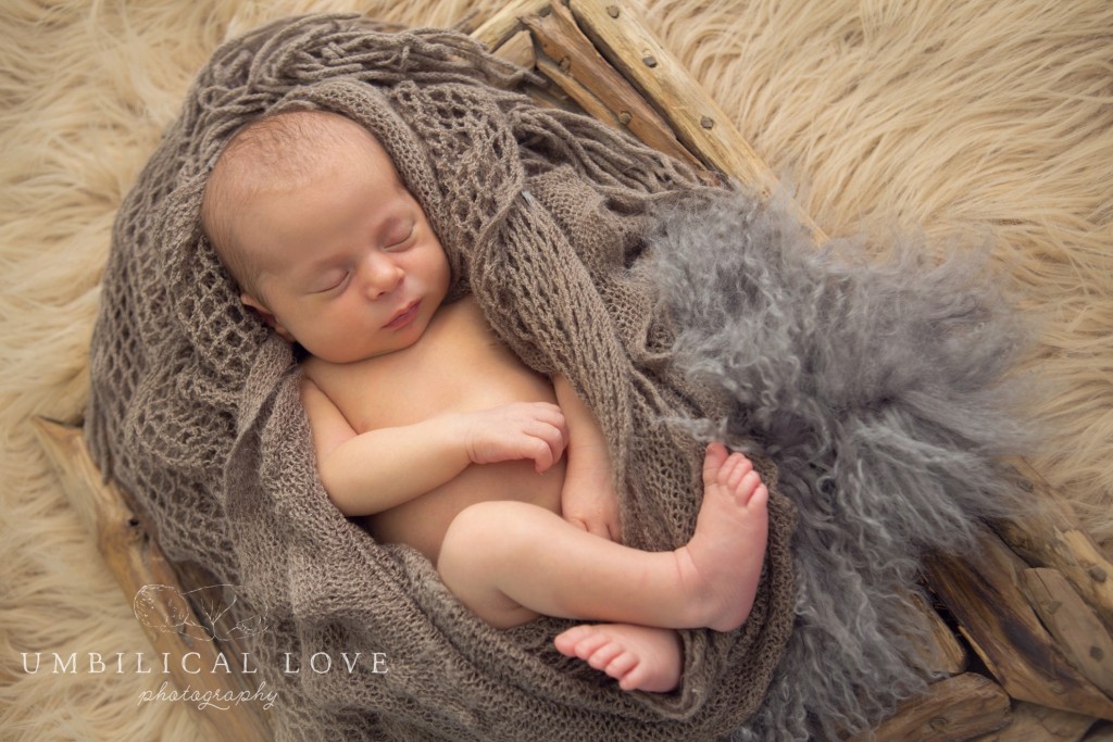 sleeping baby wrapped in soft brown blankets inside a wooden box