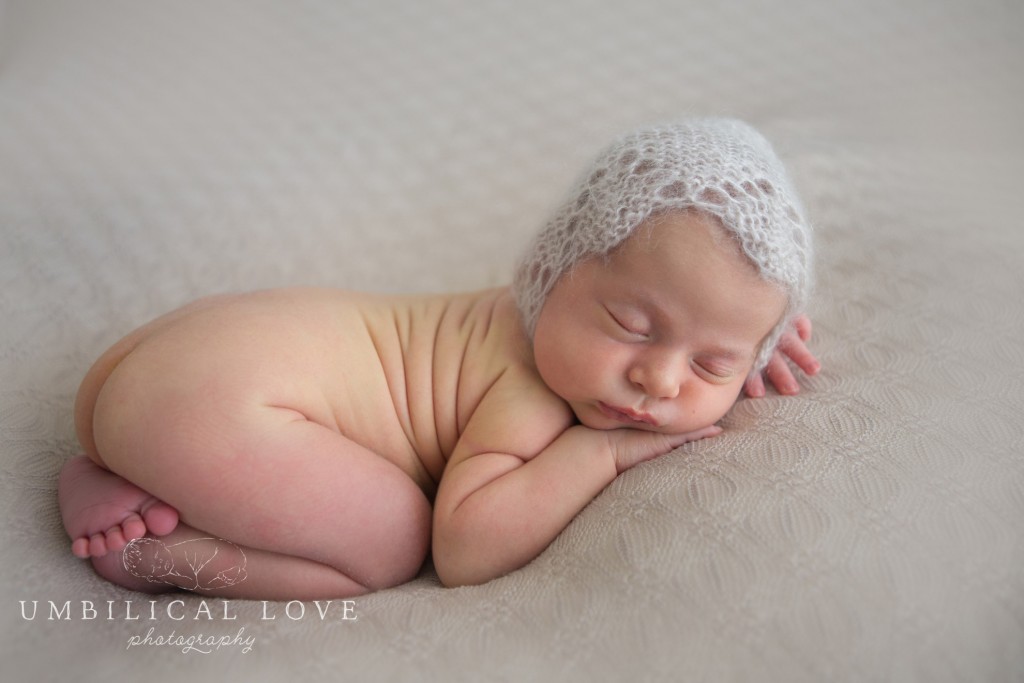 portrait of a newborn in a soft grey crochet bonnet