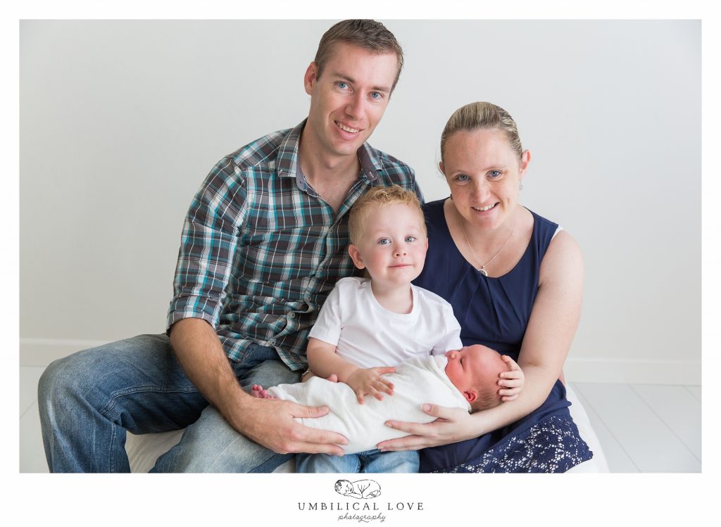 Newborn family altogether smiling at the camera