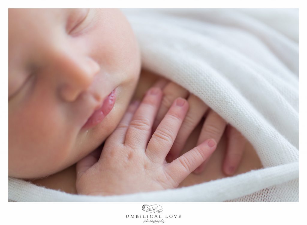 baby wrapped up in blanket with fingers crossed over on chest