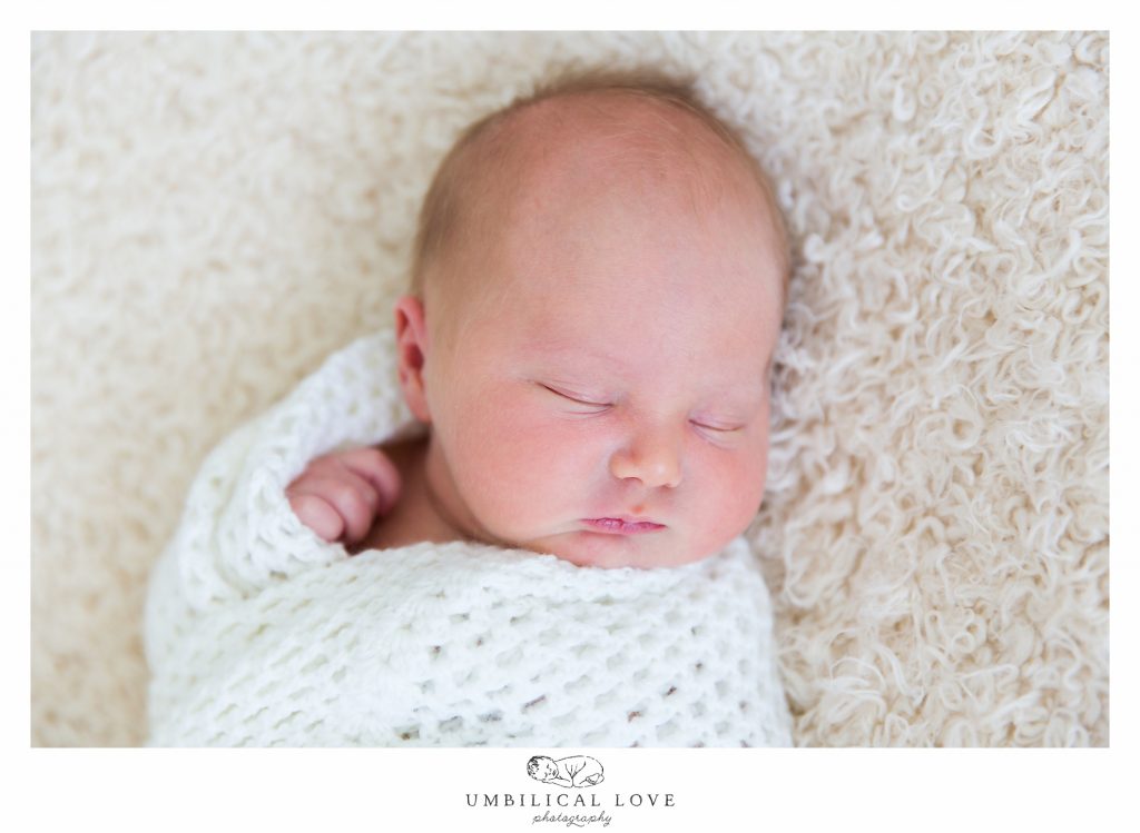 baby sleeping on wolly rug wrapped in wolly blanket