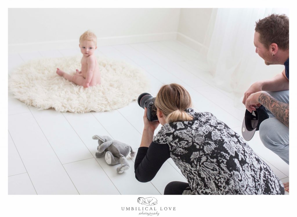 Photographer capturing a photo of little toddler sitting on a rug