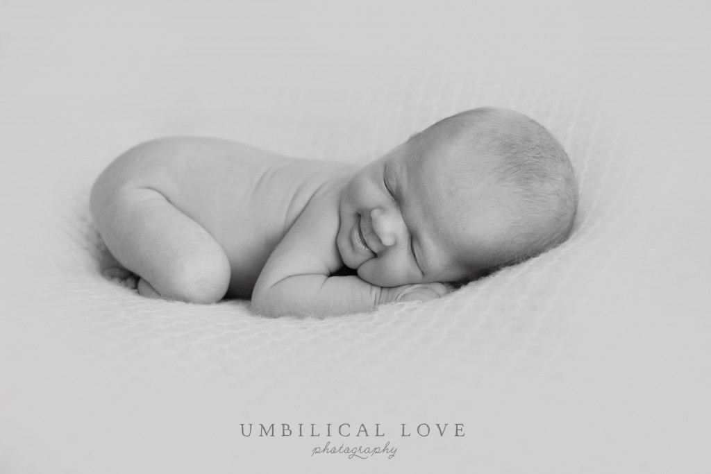 baby laying on her tummy on her hands with wind smile