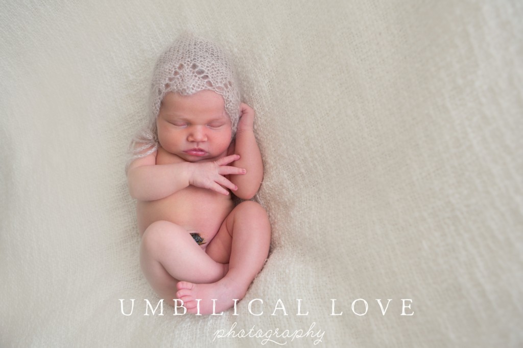 newborn sleeping on soft white blanket