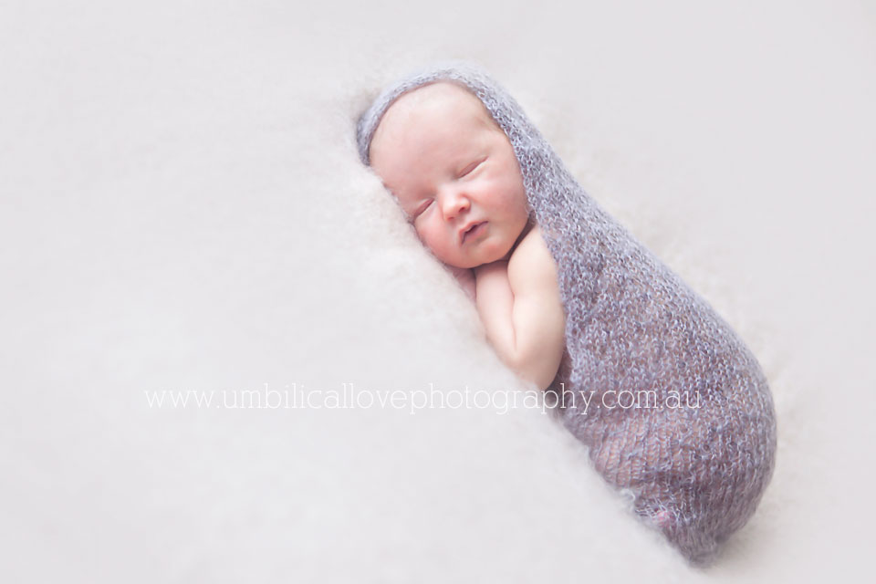 new baby wrapped up in a gorgeous knit wrap sleeping on his tummy