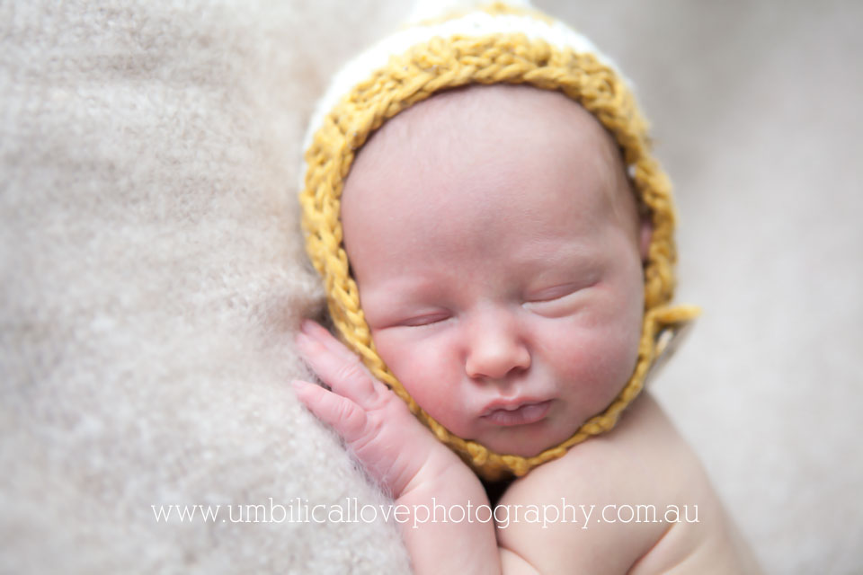 beautiful new baby with a stripy knitted hat on sleeping on his hands
