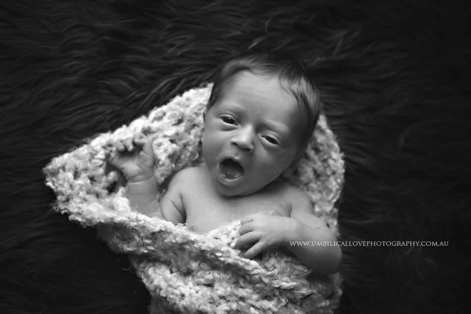 new baby boy yawning swaddled in the nude