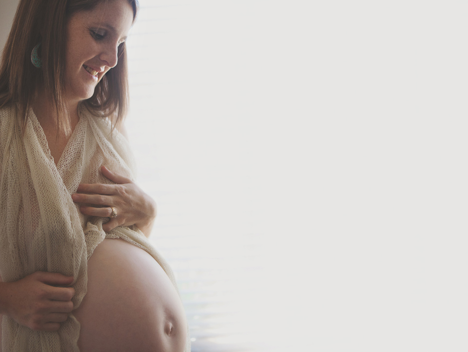 beautiful-pregnant-Mum-draped-In-Material-looking-down-at-her-pregnant-belly
