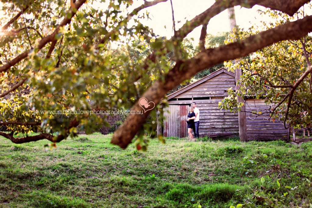 maternity couple standing next to a old shed holding her belly