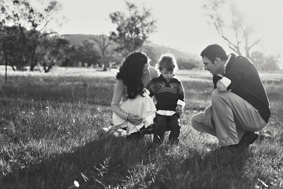 mum and dad with baby bending down in the field