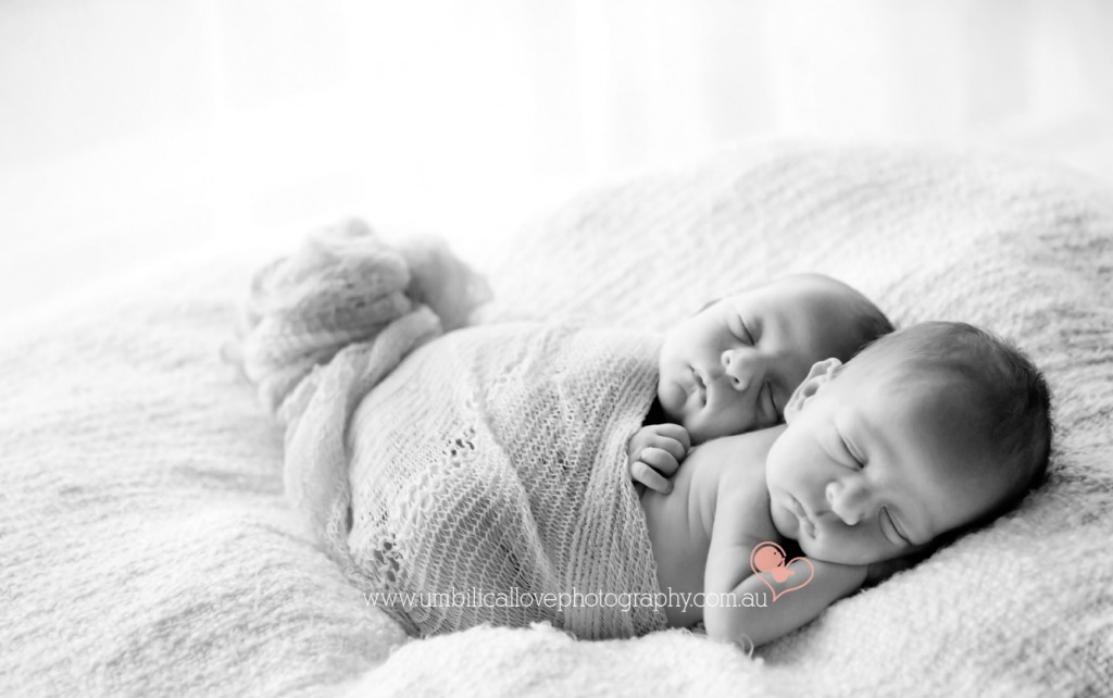 New Babie identical twins wrapped up together hugging