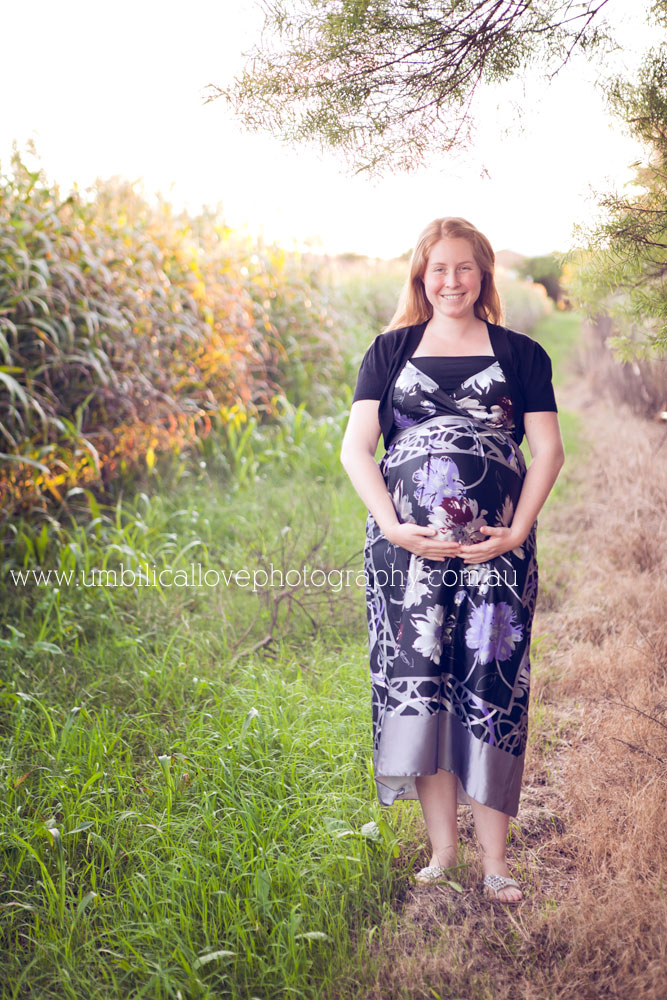 pregnant lady holding belly in the fields