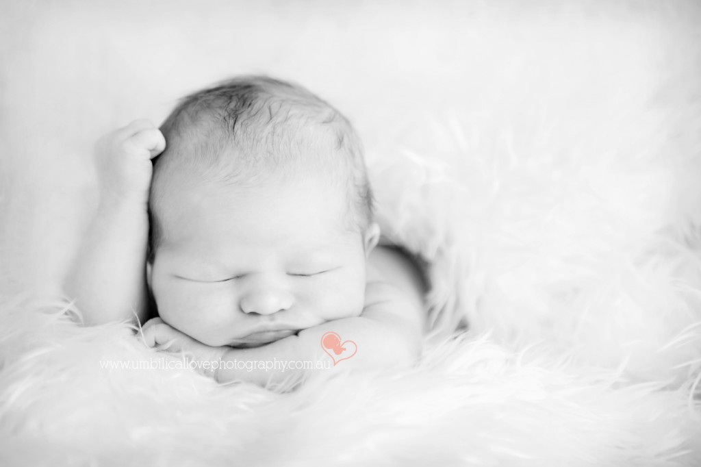 A very new baby sleeping with arm resting on head