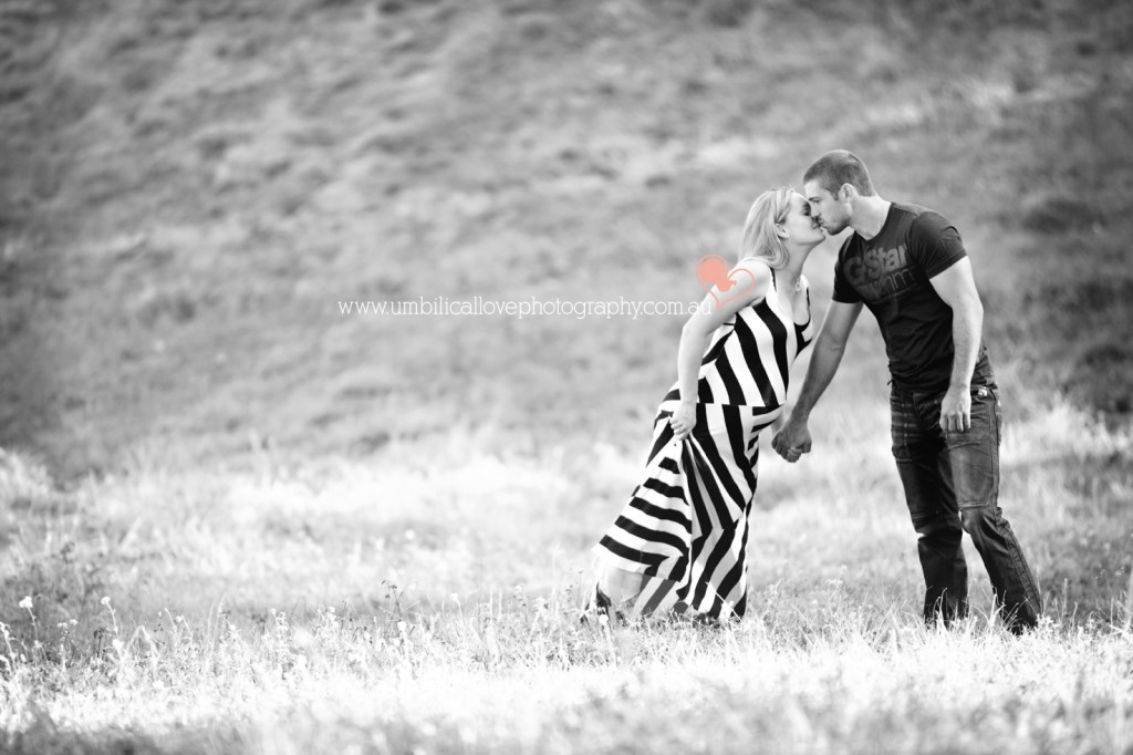 leaning over kissing while holding her pregnant belly