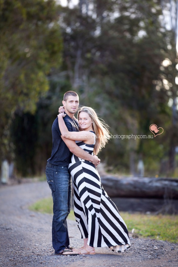 Couple expecting their first baby having a huge cuddle on a driveway on a farm