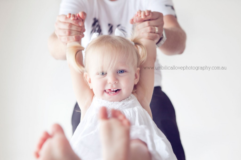Sunshine-Coast-Toddler-Photographer dad swinging his toddler in the air with toddler giggling
