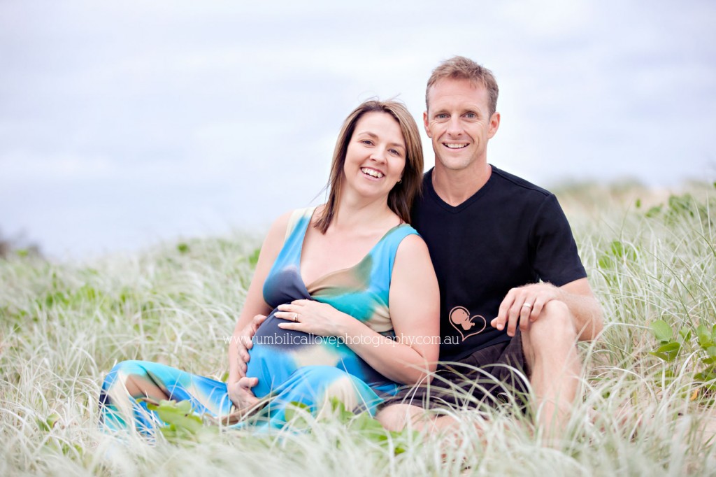 Pregnancy portrait with husband sitting on the beach dunes