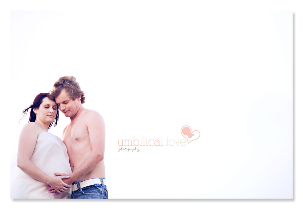 husband holding his heavily pregnant wife tummy on the beach with closed eyes